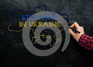 girl draws a map of Ukraine with the text Stop War in Ukraine on the blackboard