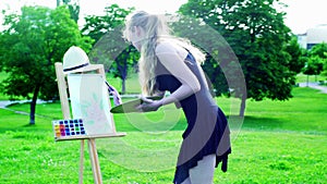 Girl draws on plein air on green grass in park