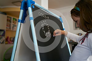 Girl draws a virus on the blackboard at home. coronavirus concept