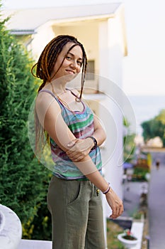 a girl with a dreadlocked hairstyle poses in the summer outdoor