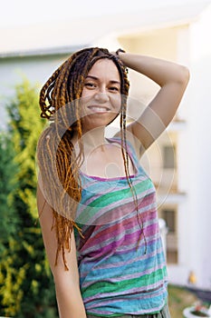 a girl with a dreadlocked hairstyle poses in the summer outdoor