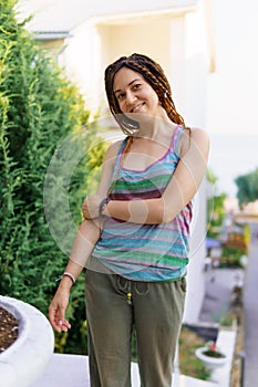 a girl with a dreadlocked hairstyle poses in the summer on the street