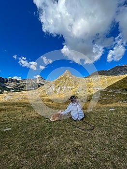 Girl with dreadlocks enjoying mountain views with her dog.