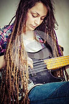 Girl with dreadlocks plaing on bass guitar
