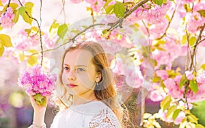 Girl on dreamy face standing under sakura branches with flowers, defocused. Tenderness concept. Girl with long hair