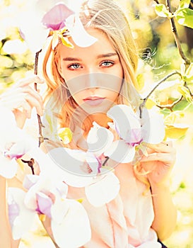 Girl on dreamy face, tender blonde near magnolia flowers, nature background. Young woman enjoy flowers in garden. Spring