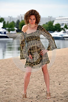 The girl in a dress with a green ornament and curly hair ashore