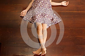 Girl in dress lying on brown wooden floor