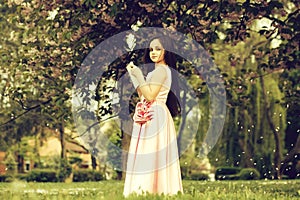 Girl in dress with notebook and pen in garden