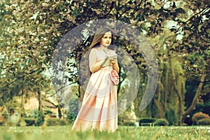 Girl in dress with notebook and pen in garden