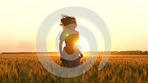 Girl in a dress running among the Golden ears of wheat. Beautiful young woman running at sunset.