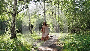 A girl in a dress runs along a forest path. Summer mood.