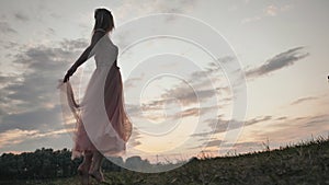 The girl in the dress swirls magically at sunset.