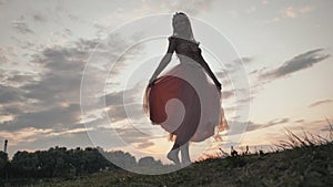 The girl in the dress swirls magically at sunset.