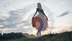 The girl in the dress swirls magically at sunset.