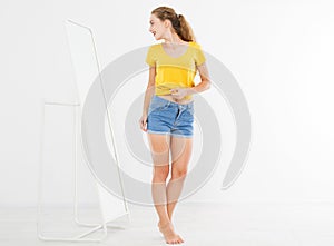 Girl dress up and try on clothes looking in mirror. Shopping and weight loss concept. Copy space. Blank template background. Body