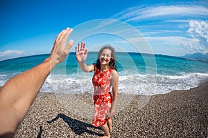 A girl in a dress walks along the beach and looks at the sea