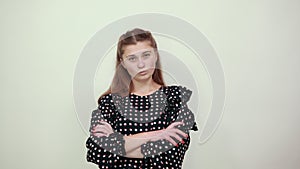 Girl in dress with white circles irritably crossed her hands and looks nervously