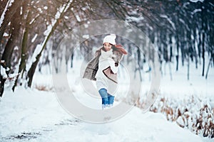 Girl is dressed in a fur vest and a white sweater runs along the snow-covered road.