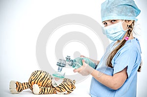 A girl dressed in a surgical suit holds an ambassador over a toy tiger and makes artificial lung ventilation.