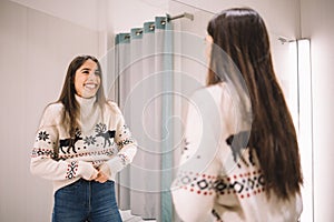 Girl dressed with sweater and jeans smiling at mirror
