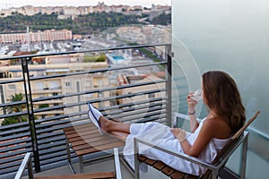 Girl dressed in towel sitting on balcony on photo