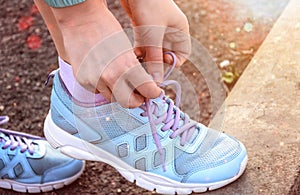 Girl dresses up blue sneakers on a sunset background