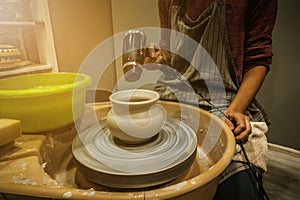 Girl dries hair dryer ceramic clay pot on a Potter`s wheel. Woman making a handmade clay pot in the workshop