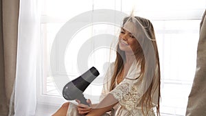 Girl dries hair with a hair dryer