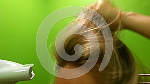 Girl dries hair with a hair dryer close-up.