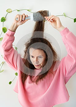 The girl dries her hair on a brush. Hair care. The concept of home care, drying healthy hair with a hair dryer and brush