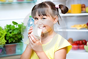 Girl drink milk standing near refrigerator