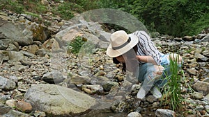 A girl drinking clean water from a mountain river in the Alpine mountains. Ecology. Tourism and hiking. Leisure. Healthy