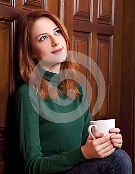 Girl drinking coffee near wood doors.