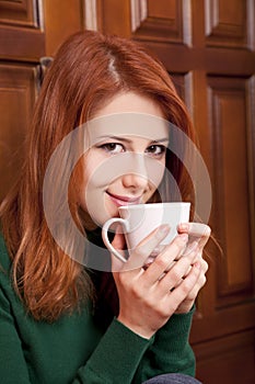 Girl drinking coffee near wood doors.