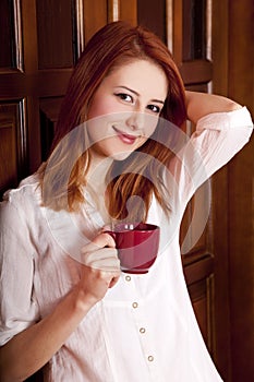 Girl drinking coffee near wood doors.