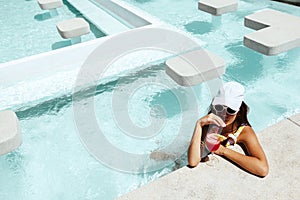 Girl drinking fruit cocktail in pool