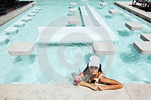 Girl drinking fruit cocktail in pool