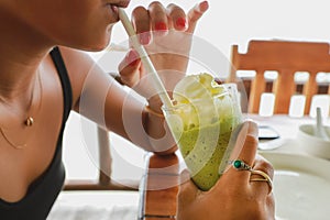 Girl drinking green tea smoothie with white cream over
