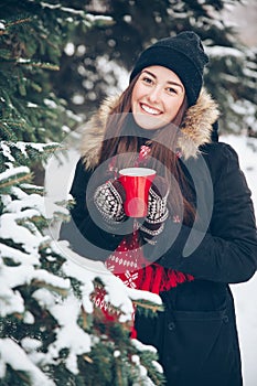 Girl drinking hot tea in the winter forest