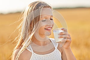 Girl drinking milk from glass on cereal field