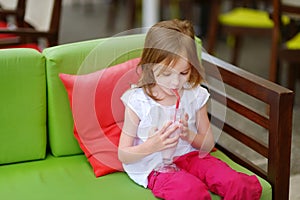 A girl drinking milkshake in outdoor restaurant