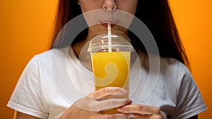 Girl drinking orange juice, adheres healthy diet and vitamin balance, closeup