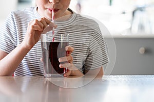 Close Up Of Girl Drinking Sugary Fizzy Soda From Glass With Straw photo