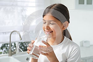 Girl drinking tap water from glass in kitchen