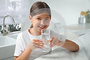 Girl drinking tap water from glass in kitchen