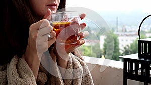 Girl is drinking tea with lemon while sitting at the balcony