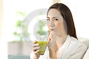 Girl drinking a vegetable green juice looking at you