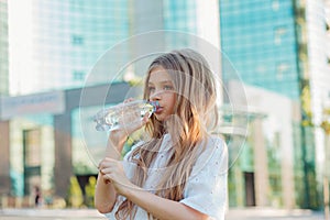 Girl drinking water from a bottle in the city