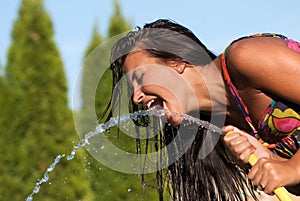 Girl drinking water from a hose